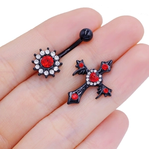 Close-up of black metal belly rings with red crystals in sun and cross shapes