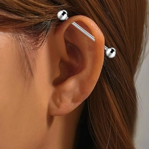 Detailed view of a polished titanium industrial barbell earring on a model ear