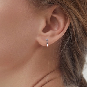 Close-up of polished titanium cone pendant earring on ear showing high-shine metal finish