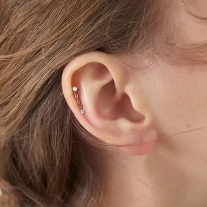 Close-up of titanium cartilage piercing featuring a sparkling zircon pendant with chain