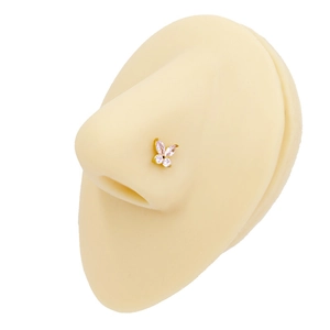 Detail view of a golden butterfly nose stud with pink zircons on a silicone nose model