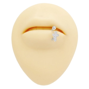 Dettaglio del piercing labbro in acciaio inossidabile con pendente a croce di cristallo