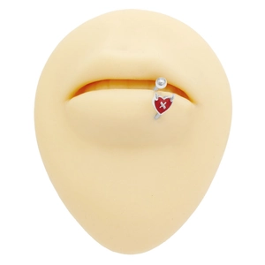Primo piano di un piercing al labbro a cuore di diavolo rosso su un modello in silicone