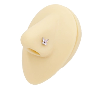 Macro shot of butterfly nose stud with pink zircon on flesh-colored silicone model