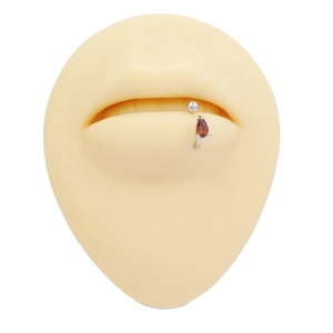 Macro shot of silver titanium lip ring with pear-cut brown zircon on silicone model