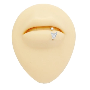 Macro detail of silver butterfly labret stud on silicone lip model with zircon butterfly design