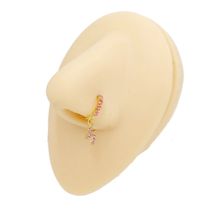 Dettaglio di un anello al naso dorato con strass rosa e ciondolo a forma di fulmine