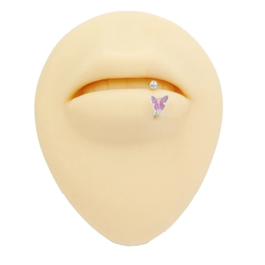 Close-up of titanium butterfly lip stud with pink enamel and sparkling zircon detail