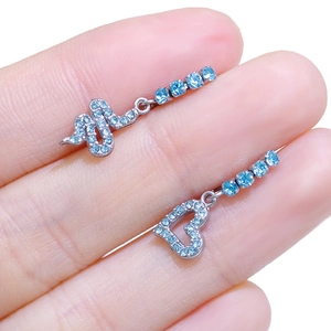 Detailed shot of asymmetric snake and heart earrings with light blue crystals in hand