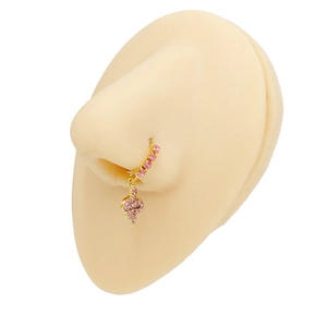 Dettaglio di un anello al naso dorato con strass rosa e pendente a forma di serpente