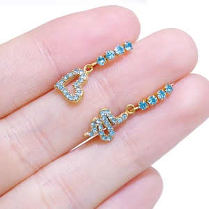 Detailed shot of gold-plated snake and heart earrings with light blue rhinestones