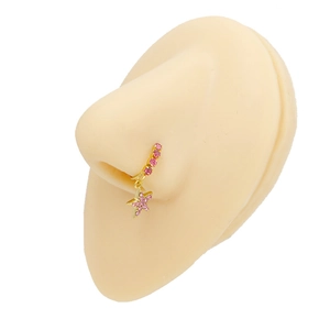 Dettaglio di un anello al naso dorato con strass rosa e ciondolo a stella su un modello