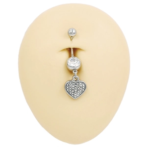 Detalle de piercing de ombligo de corazón plateado con circonitas en modelo de silicona