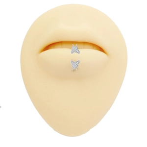 Detailed view of butterfly labret stud on silicone lip model made of silver titanium steel