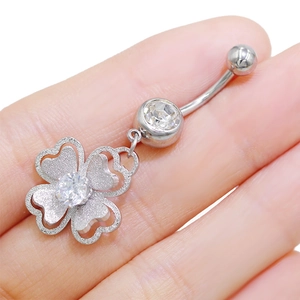 Primer plano de piercing de ombligo de trébol plateado con cristal brillante incrustado