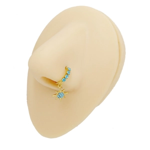 Detailed view of a gold nose ring with light blue crystals and a star pendant on a nose model