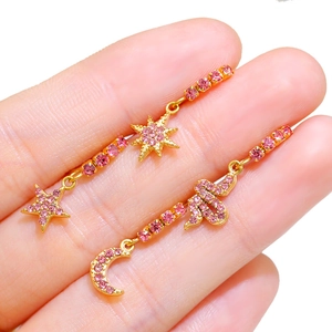 Orecchini pendenti con stelle e luna in strass rosa e finitura dorata in mano