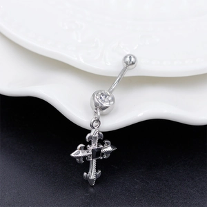 Macro shot of silver navel ring with gothic cross pendant and black stone inlay