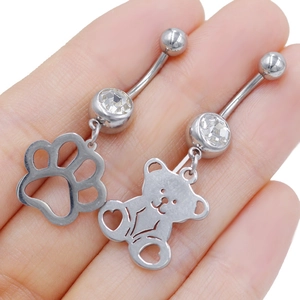 Detail of stainless steel belly rings with teddy bear and paw print charm pendants