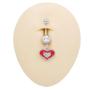 Dettaglio macro di un piercing all'ombelico con cuore, smalto rosso e zirconi