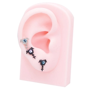 Macro shot of bat wing ear studs with evil eye gems and star cross pendants on model