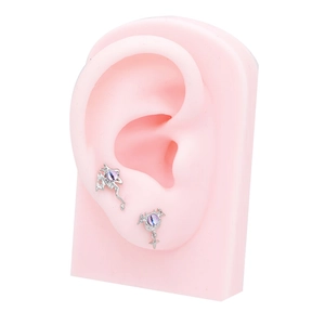 Close-up of gothic bat wing ear studs with purple stones on a silicone ear model