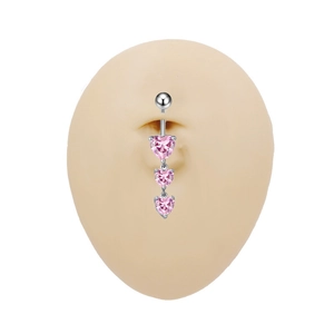 Dettaglio del piercing per ombelico con tre zirconi a cuore rosa su modello