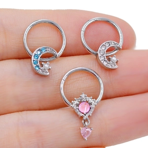 Macro view of stainless steel nose rings featuring moon and crown designs on fingertips