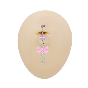 Dettaglio del fiocco di seta rosa e della catena a cuore sul piercing all'ombelico argento