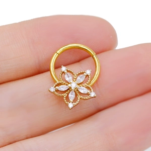 Macro view of a gold nose ring featuring a five-petal flower set with white zircons