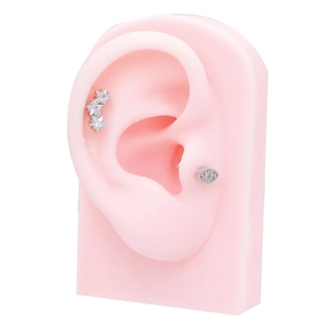 Detail of silver heart and star studs on a pink silicone ear model showing placement