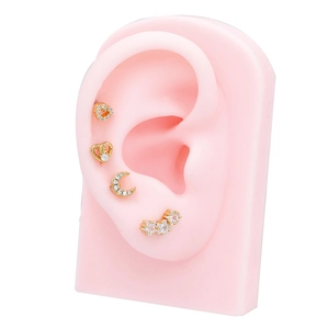 Detail of gold-plated stud earrings set with star, heart, and moon zirconia shapes