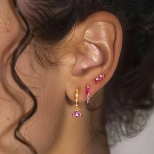 Detalle de pendientes y earcuff con circonitas rosas y metal dorado en la oreja