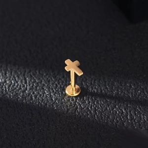 Gepolijste gouden titanium kruis piercing op een luxe zwarte leerachtige achtergrond
