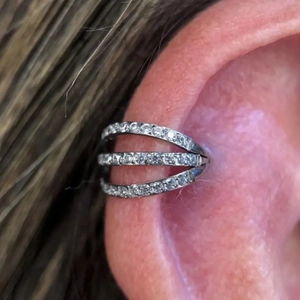 Macro view of triple-row sparkling diamond ear cuff in silver-tone F136 titanium metal