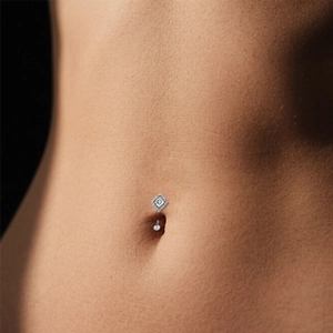 Macro shot of silver G23 titanium belly ring with diamond-shaped zircon on skin