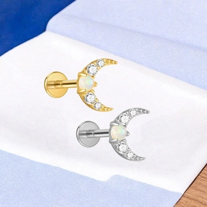 Macro-opname van gouden en zilveren maan labret studs met opaal en zirkonia pavé