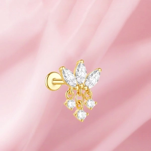 Detalle de piercing de oreja de titanio dorado F136 con cristales en seda rosa