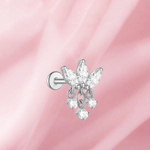 Detalle de piercing de titanio F136 con borlas de circonitas sobre seda rosa