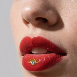 Macro-opname van een gouden F136 titanium lip-piercing in de vorm van een zon met kristal