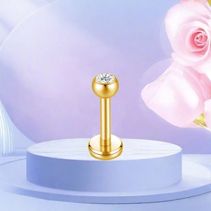 Detail view of gold titanium labret stud with white zircon on marble pedestal