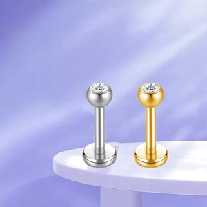 Detailed close-up of gold and silver titanium labret studs with inlaid round crystals