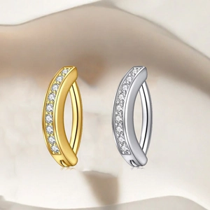 Makroaufnahme von gebogenen Bauchnabelpiercings mit weißen Zirkonia in Gold und Silber