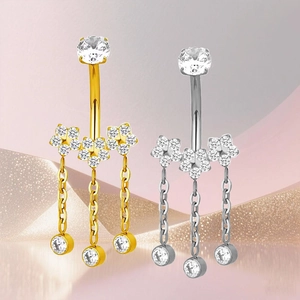 Detalle de piercings de ombligo en titanio con flores de circón y cadenitas