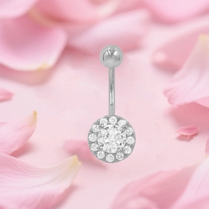 Piercing de ombligo plateado con circonita redonda y halo sobre fondo floral rosa