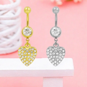 Primo piano dettagliato di piercing all'ombelico a forma di cuore in oro e argento con strass