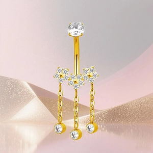 Detalle de un piercing de ombligo en titanio dorado con flores de circón y flecos