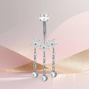 Detalle del piercing de ombligo en titanio F136 con flores de circonita y borlas colgantes