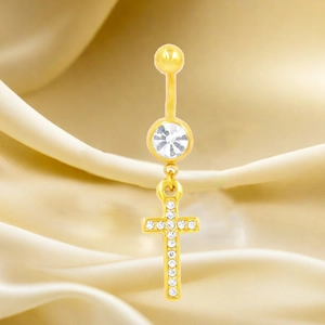 Macro di un piercing all'ombelico placcato oro con pendente a croce in cristallo
