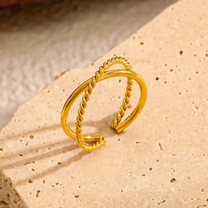 Minimalist 18k gold plated stainless steel twisted cross ring on a stone pedestal